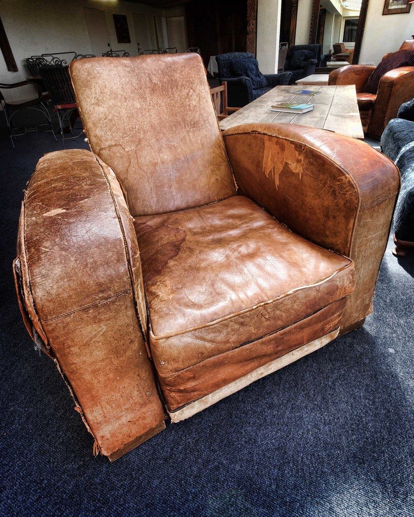 A worn leather armchair beside a desk in a cozy study