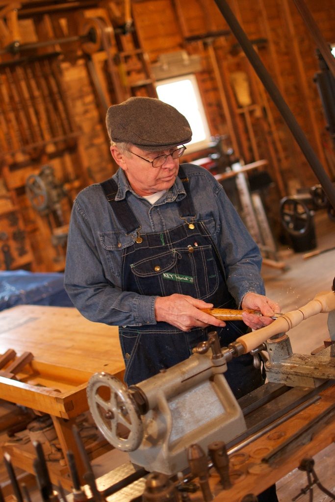 A craftsman shaping wood at a traditional workbench